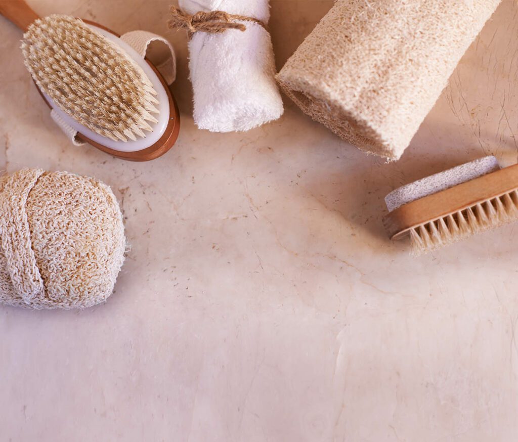 Natural bath accessories including brushes and loofahs on a beige surface.