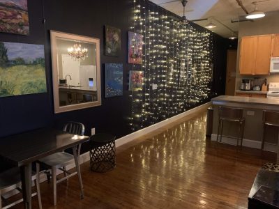 Cozy restaurant interior with wine bottles displayed on a wall and reflective wooden flooring.