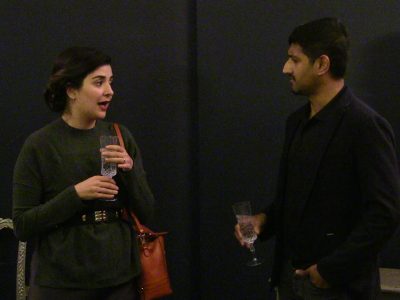 Two people having a lively conversation, each holding a drink.