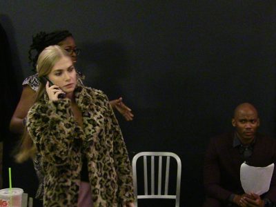 A woman in a leopard print coat talking on a phone with two people in the background.