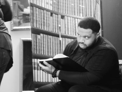 Man reading book in library, glancing sideways