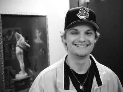Smiling young man with baseball cap, painting background