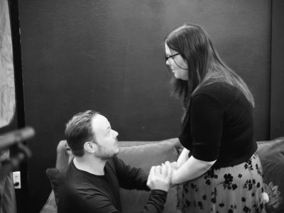 Black and white couple holding hands on couch